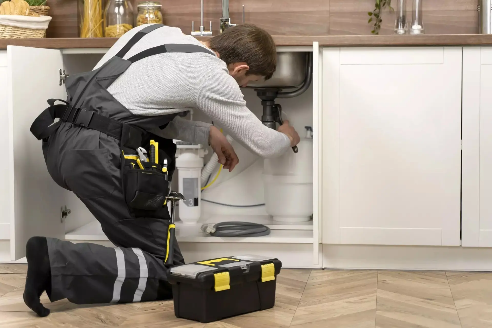 Gasfitero trabajando bajo el lavadero de una cocina con su caja de herramientas