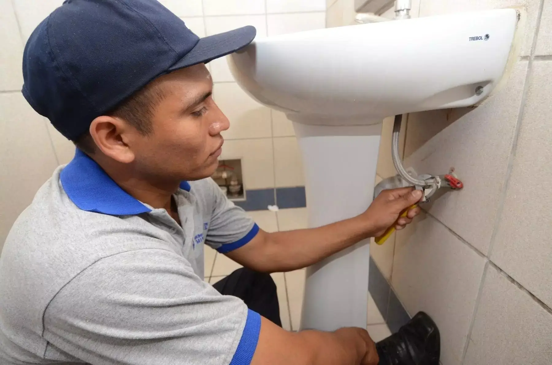 Gasfitero reparando la conexión de agua de un lavatorio en un baño